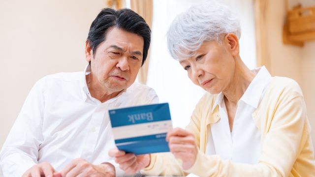 高齢夫婦が通帳を見ながら給付金や助成金について相談している様子